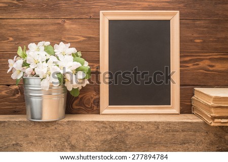 Wooden frame, flowers and old books on wooden background
