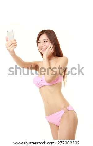 young Japanese woman in a pink bikini takes a selfie