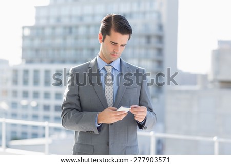 Smiling businessman texting with his mobile phone at the patio