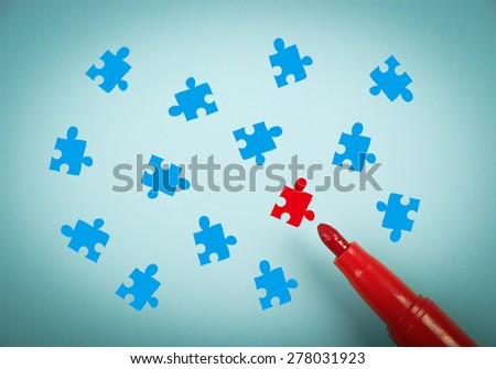 Puzzle concept is on blue paper with a red marker aside.