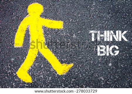 Yellow pedestrian figure on the road walking towards THINK BIG. Conceptual image with Text message over asphalt background.