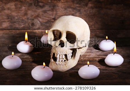 Still life with human skull and candles on wooden background