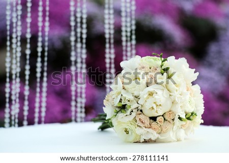Beautiful delicate wedding bouquet of roses and peony in pastel colours lying on table in broad daylight outdoor on purple and violet holiday background copyspace, horizontal picture