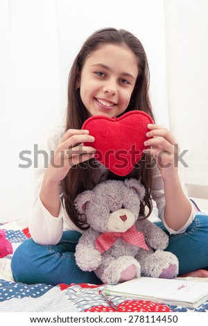 
Girl with toy heart and teddy bear