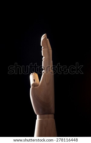 A hand of wood doll make four fingers to four(4) isolated black background with back light in the studio.