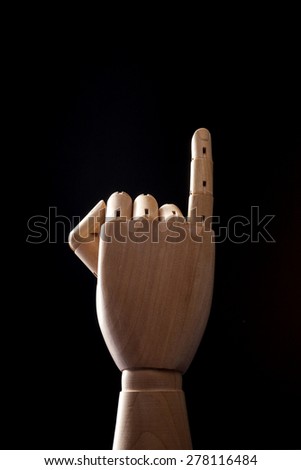 A hand of wood doll make little finger to promise isolated black background with back light in the studio.