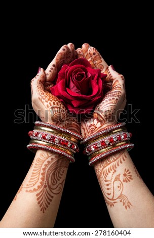 Woman hands with henna holding red rose isolated on black background with clipping path 