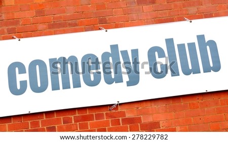 Comedy club sign against red brick wall