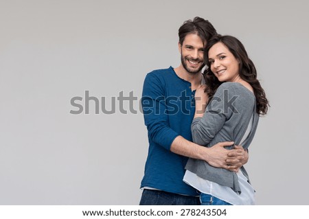 Portrait of happy couple looking at camera against gray background

