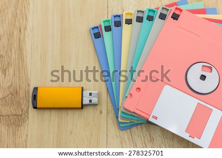 Stack of colorful floppy disks and a flash drive on a wooden table