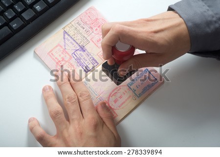 Immigration control officer will arrival stamp in the passport Royalty-Free Stock Photo #278339894