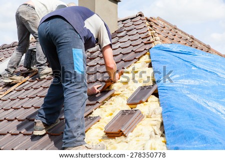 a roofer laying tile on the roof Royalty-Free Stock Photo #278350778