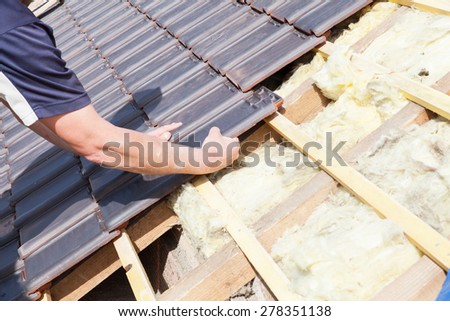 a roofer laying tile on the roof Royalty-Free Stock Photo #278351138
