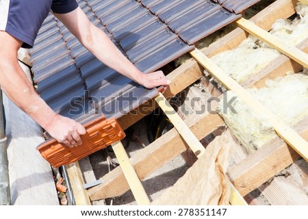 a roofer laying tile on the roof Royalty-Free Stock Photo #278351147