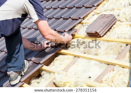 a roofer laying tile on the roof Royalty-Free Stock Photo #278351156
