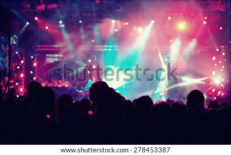 Cheering crowd in front of bright colorful stage lights - retro styled photo 
