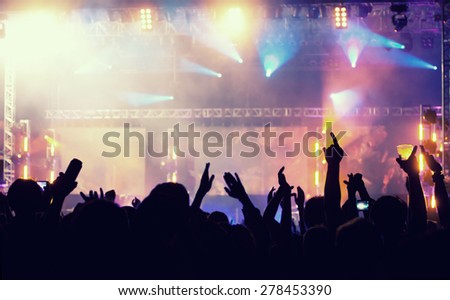 Cheering crowd in front of bright colorful stage lights - retro styled photo 