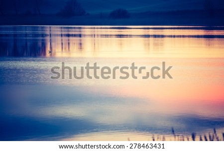 Vintage photo of beautiful sunset over calm lake. Landscape photographed in Mazury lake district.
