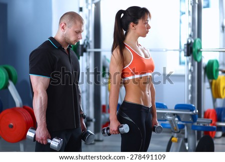 Beautiful woman at the gym exercising with her trainer