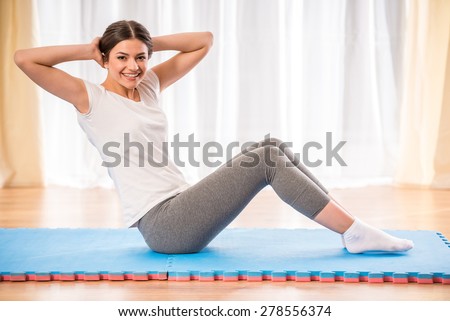Young pretty athletic girl doing abs on a floor at home.