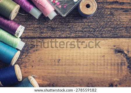 Sewing threads on grunge wooden background with free space.