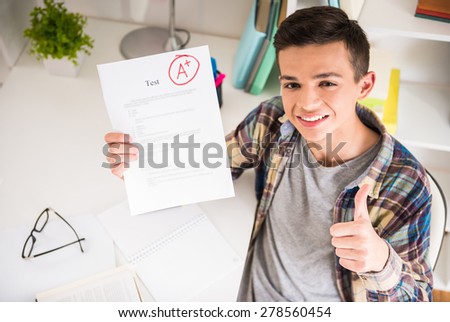Portrait of teenager sitting at the table at home and showing perfect test results. Royalty-Free Stock Photo #278560454