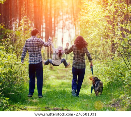 Happy family walking with dog in the forest Royalty-Free Stock Photo #278581031