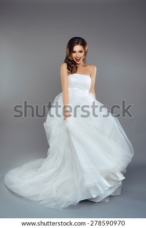 Portrait of a Beautiful Bride Model in a White Wedding Dress with Elegant Curly Hairstyle and Red Lips
