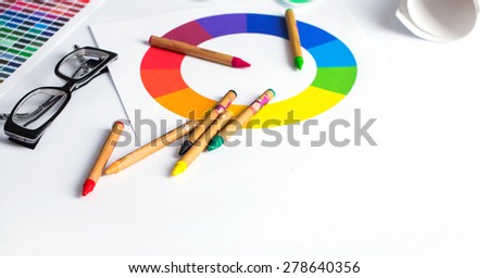 color pencils, colored palette and glasses on wooden table