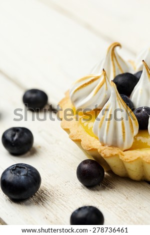 Tartlet with lemon curd, blueberries and meringue vertical close-up