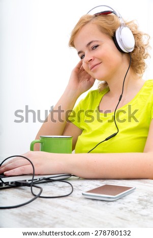 A young plus size woman listening to Audio in front of a laptop computer.
