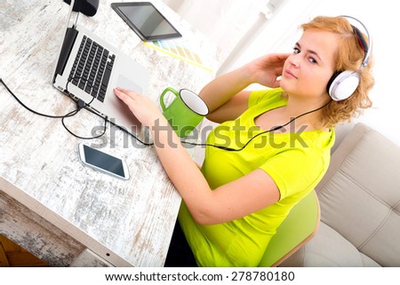 A young plus size woman listening to Audio in front of a laptop computer.
