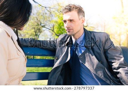 Portrait of a beautiful couple talking on the bench outdoors. Looking at each other