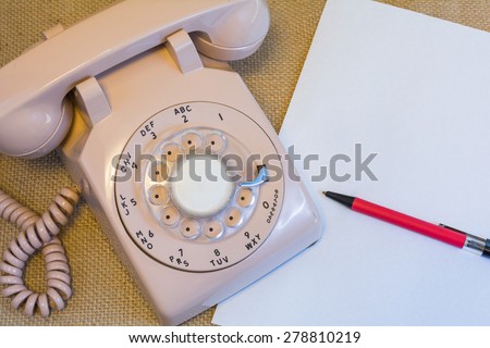 Rotary phone with blank paper and pen.