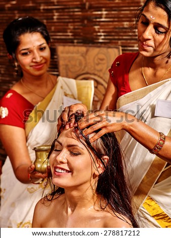 Young woman having head ayurveda spa treatment. Two masseuses.