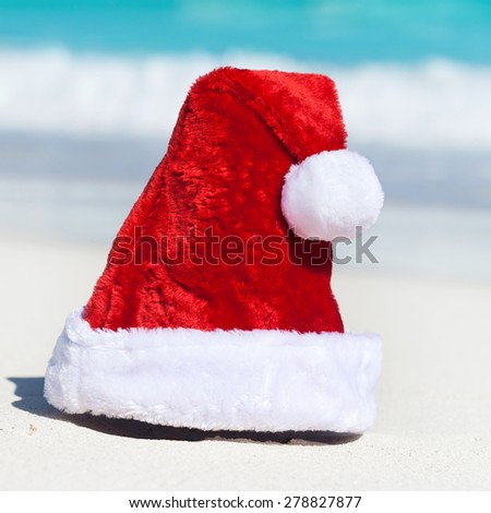 Santa Hat on white sandy beach on Caribbean sea background, New Year holiday concept