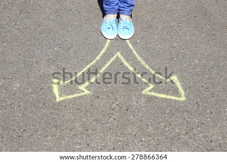 Female feet making choice on asphalt with drawing arrows, outdoors
