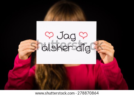 Studio shot of child holding a sign with Swedish words Jag Alsker Dig - I Love You
