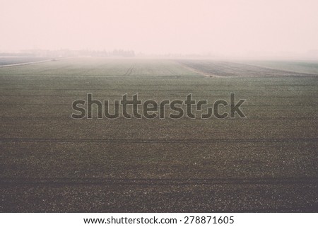 countryside fields in early spring with clouds and farmland - retro vintage grainy film look