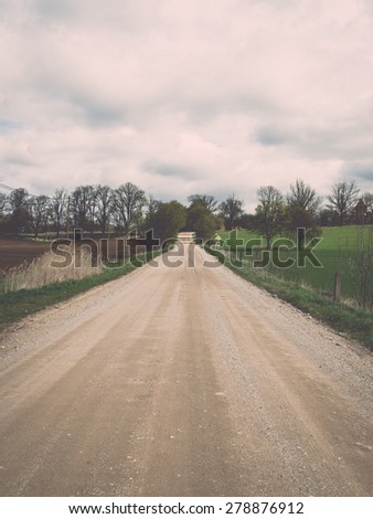 empty country road in spring with perspective and shadows - retro vintage grainy film look