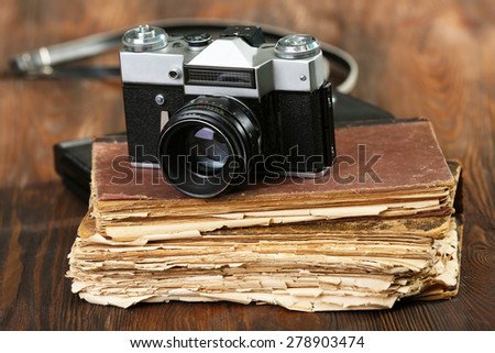 Retro camera with old book on table on green background