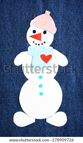 Handmade snowman on dark jeans background