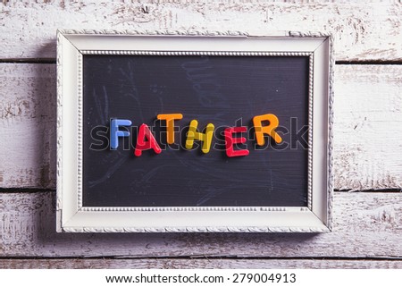 Picture frame with Father sign laid on wooden floor backround.