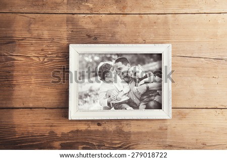 Picture frame with family photo laid on a wooden background.