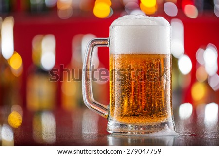 Bottle of beer with glass on bar desk, close-up.