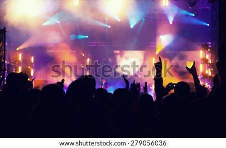 Cheering crowd in front of bright colorful stage lights - retro styled photo