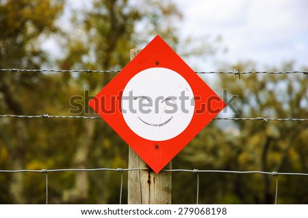 Stop sign with smile attached to barbed wire fence. Never stop smiling / Be positive concepts.