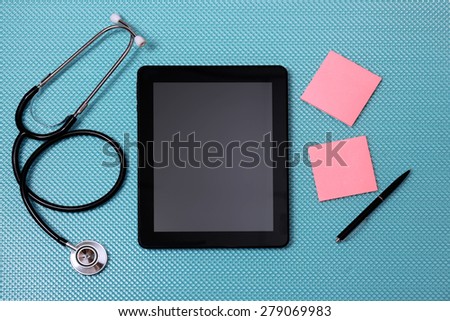 Medical tablet with stethoscope on blue background