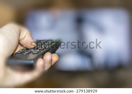 Close up of remote in hand with shallow depth of field during television watching Royalty-Free Stock Photo #279138929