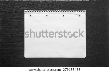White empty paper sheet on black stone background. School book page